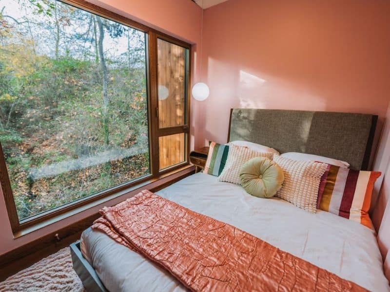 Warm bedroom in The Ellwood shipping container cabin in Hocking Hills with a mid-century design with a view of the woods.