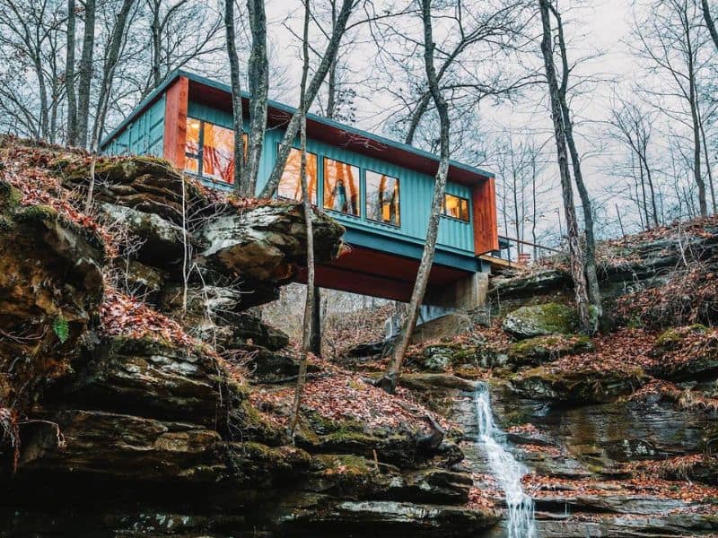 The Ellwood container cabin perched above a natural waterfall, blending modern design with rustic charm in Hocking Hills, OH.