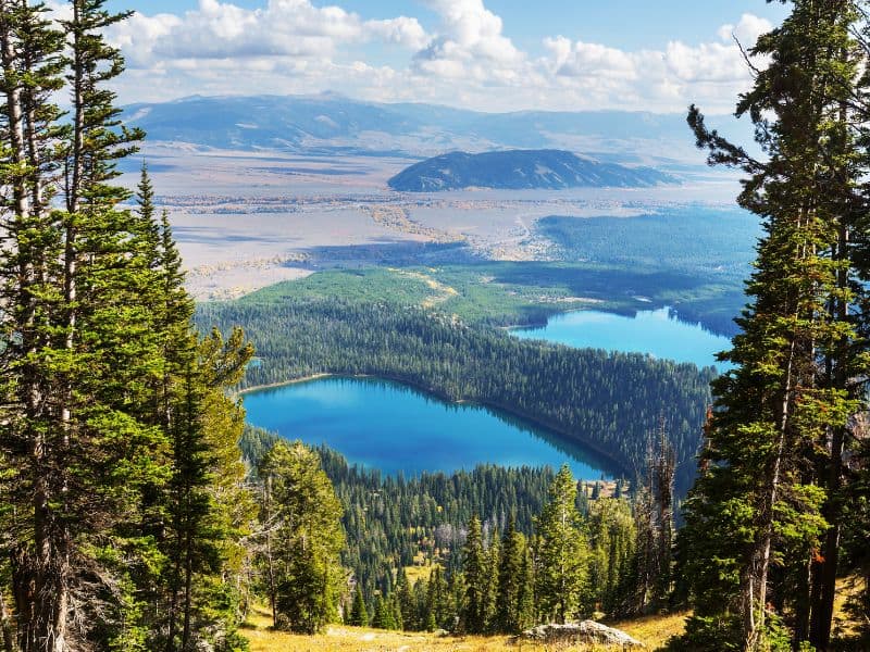 Aerial view of deep blue lakes amongst the dense forests and rolling hills of Grand Teton National Park, WY.