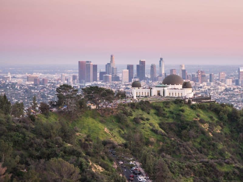 Aerial view of the Griffith Observatory at sunset with the Los Angeles skyline in the background.