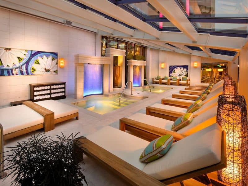 Luxurious spa at the Atlantis Casino Resort in Reno with an indoor pool area with cascading waterfalls, cushioned lounge chairs, and soft ambient lighting.